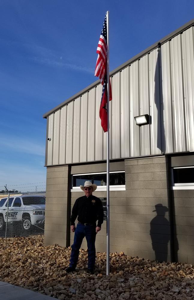 flags on pole with sheriff standing below